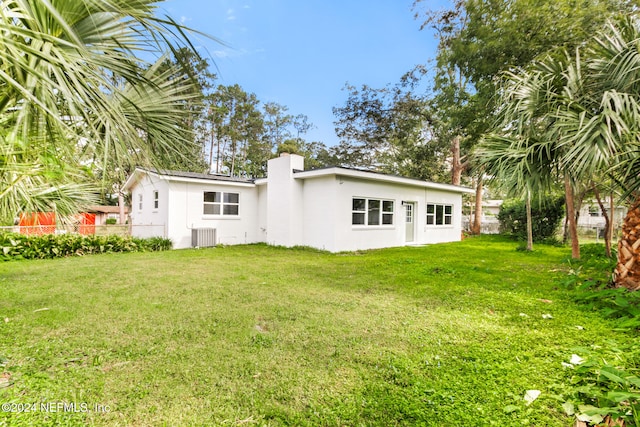 rear view of house featuring cooling unit and a yard