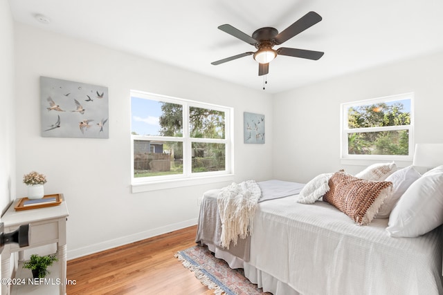 bedroom featuring multiple windows, hardwood / wood-style floors, and ceiling fan