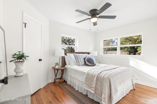 bedroom featuring wood-type flooring, multiple windows, and ceiling fan