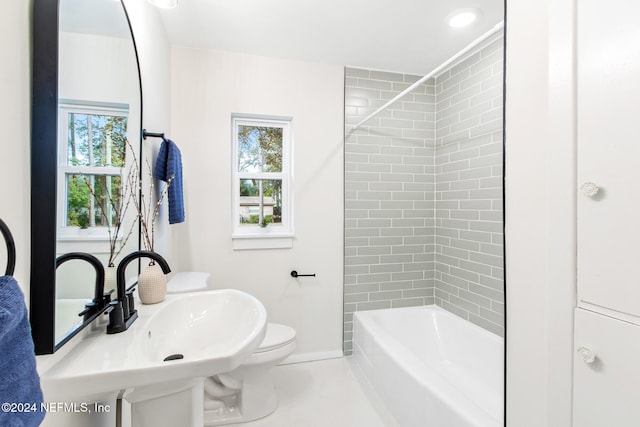 full bathroom featuring a wealth of natural light, tiled shower / bath, sink, and toilet