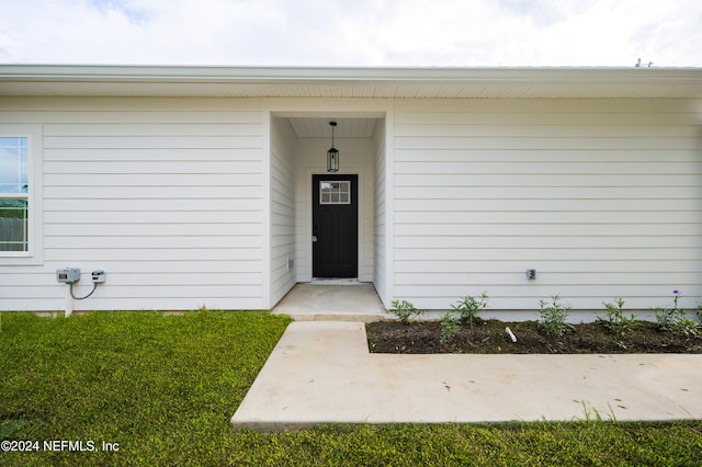 doorway to property featuring a lawn