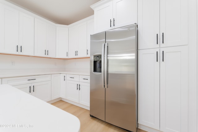 kitchen with white cabinetry, stainless steel refrigerator with ice dispenser, and light hardwood / wood-style flooring