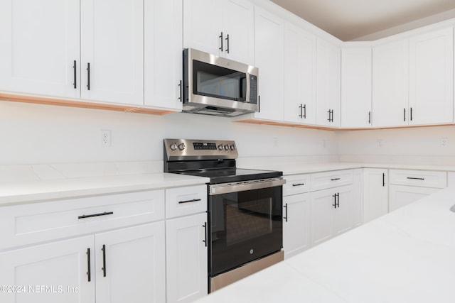 kitchen featuring light stone countertops, white cabinets, and stainless steel appliances