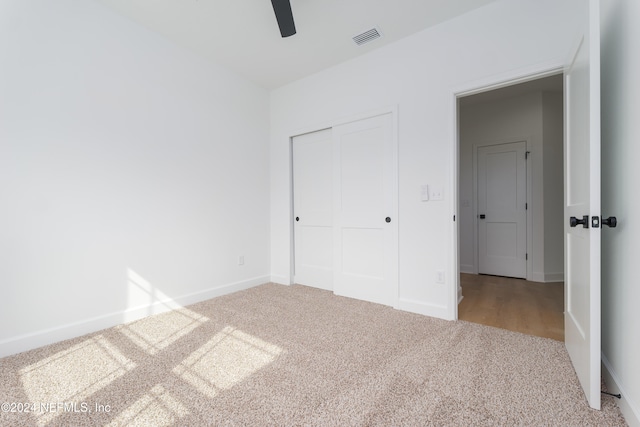 unfurnished bedroom with a closet, light carpet, and ceiling fan