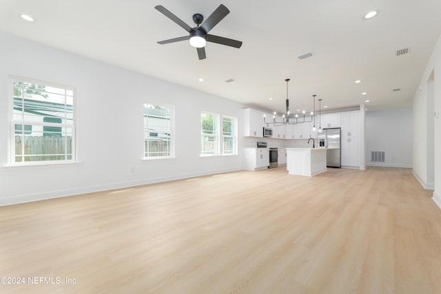 unfurnished living room with light hardwood / wood-style floors, ceiling fan with notable chandelier, and sink