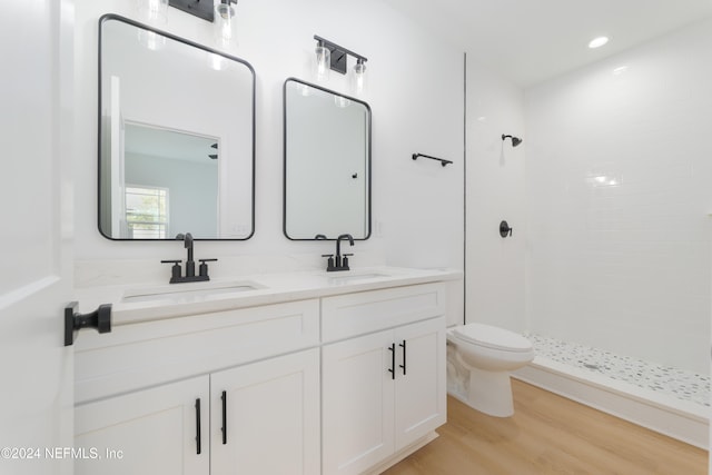 bathroom featuring toilet, vanity, hardwood / wood-style flooring, and tiled shower