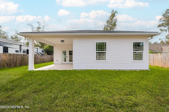 back of property with french doors, a lawn, and a patio