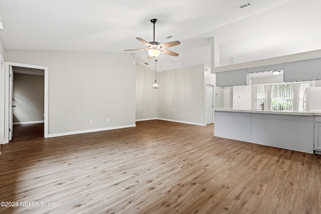 unfurnished living room with light hardwood / wood-style floors, ceiling fan, and vaulted ceiling