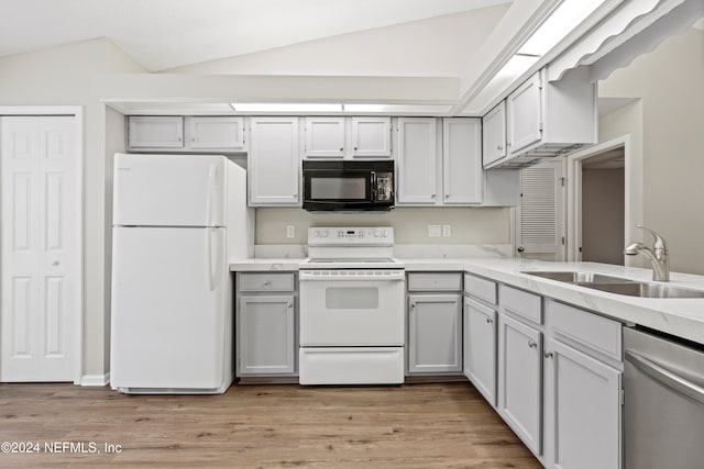 kitchen with white appliances, light hardwood / wood-style floors, sink, and lofted ceiling