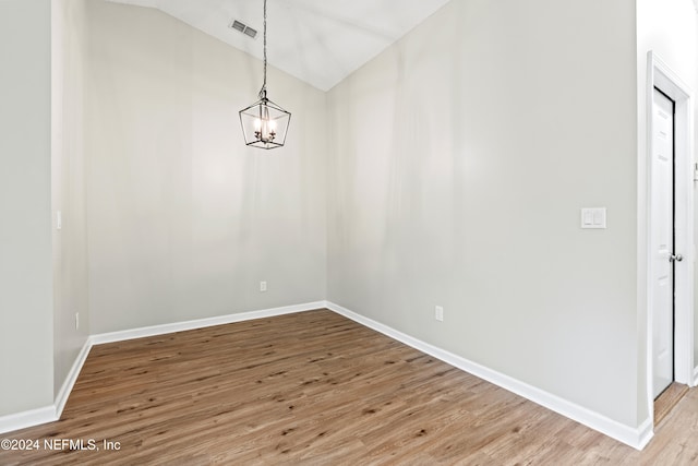 unfurnished dining area featuring a notable chandelier, hardwood / wood-style flooring, and vaulted ceiling