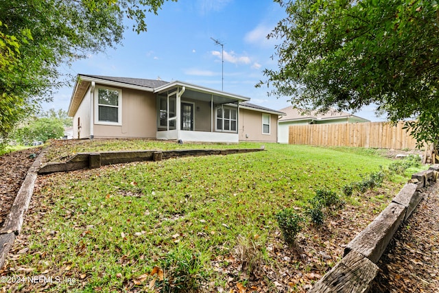 rear view of house with a sunroom and a yard