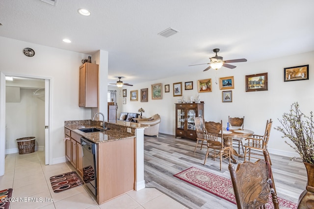 kitchen with dark stone counters, ceiling fan, sink, light hardwood / wood-style flooring, and dishwasher