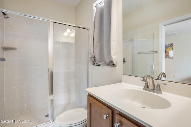 bathroom featuring a shower with door, vanity, and toilet