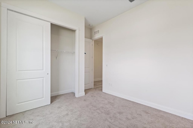 unfurnished bedroom with light colored carpet and a closet