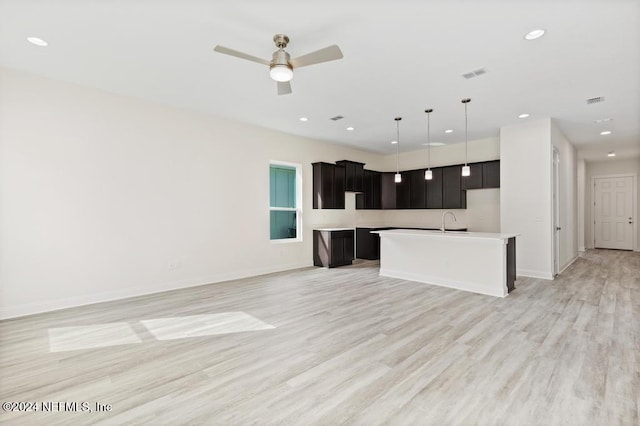 kitchen with light hardwood / wood-style floors, a center island with sink, sink, ceiling fan, and hanging light fixtures