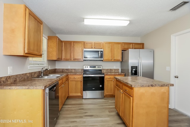 12229 Mastin Cove Rd, Jacksonville, FL 32225 - kitchen featuring appliances with stainless steel finishes, a sink, light wood-style floors, a center island, and a textured ceiling