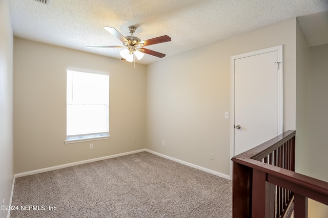 spare room featuring a textured ceiling, carpet flooring, and ceiling fan