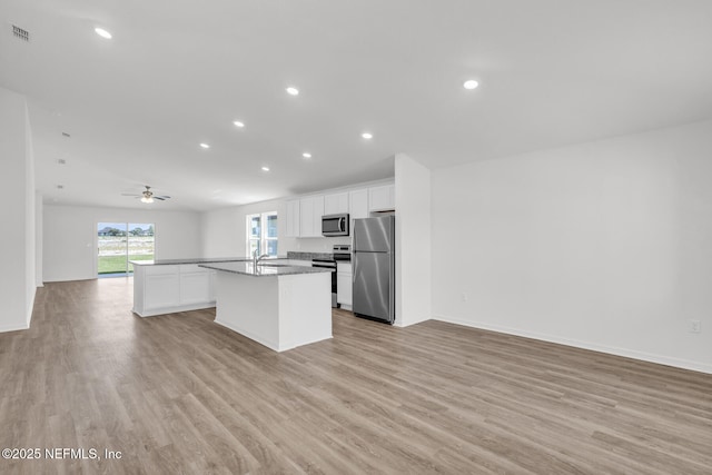 37343 Whisper Way, Hilliard, FL 32046 - kitchen with appliances with stainless steel finishes, a kitchen island with sink, open floor plan, light wood-style floors, and white cabinetry