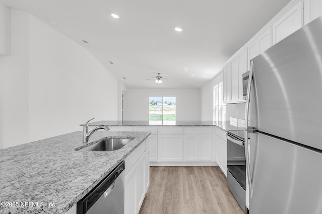 37343 Whisper Way, Hilliard, FL 32046 - kitchen featuring stainless steel appliances, a sink, light wood-style floors, white cabinets, and light stone countertops