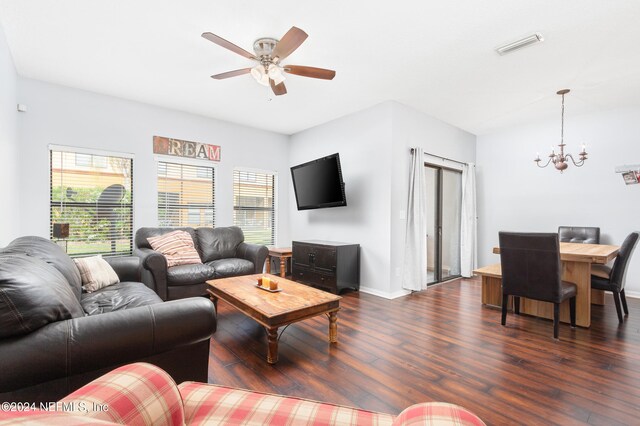 living room with dark wood-type flooring, a healthy amount of sunlight, and ceiling fan with notable chandelier