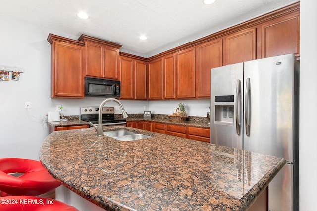 kitchen featuring sink, appliances with stainless steel finishes, a kitchen breakfast bar, dark stone countertops, and a kitchen island with sink