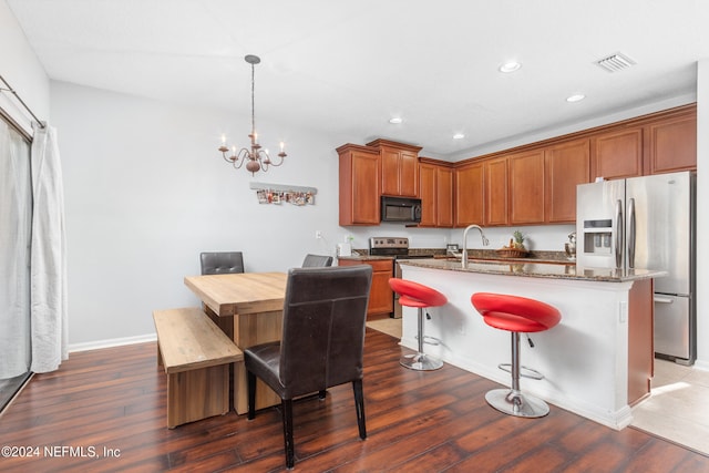 kitchen with dark wood-type flooring, dark stone counters, stainless steel refrigerator with ice dispenser, and sink