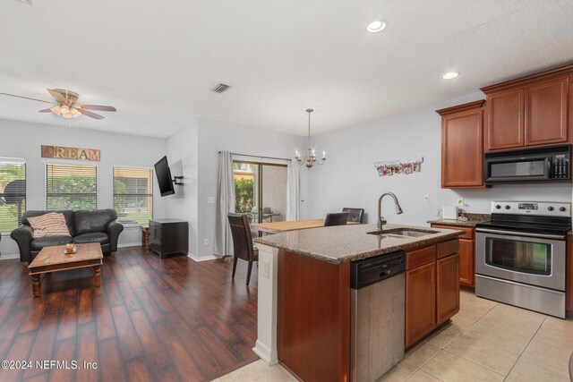 kitchen with a center island with sink, appliances with stainless steel finishes, light stone countertops, sink, and light hardwood / wood-style floors