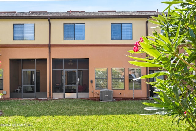 back of property featuring central AC unit, a sunroom, and a yard