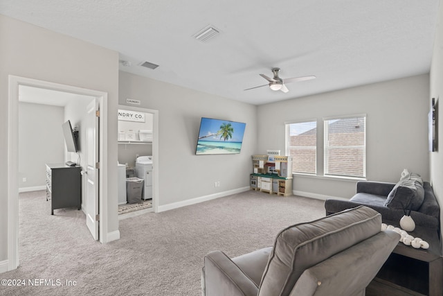 carpeted living room featuring ceiling fan and washer / clothes dryer