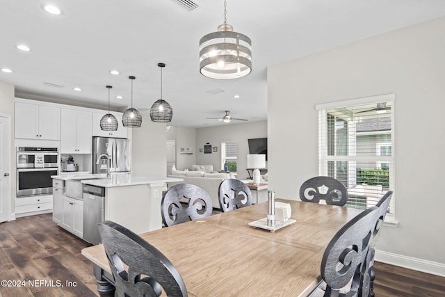 dining room with ceiling fan with notable chandelier, dark hardwood / wood-style flooring, and sink