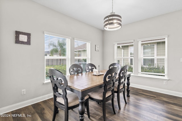 dining area with dark wood-type flooring, an inviting chandelier, and plenty of natural light