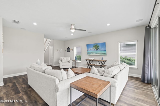 living room with dark wood-type flooring, ceiling fan, and a healthy amount of sunlight