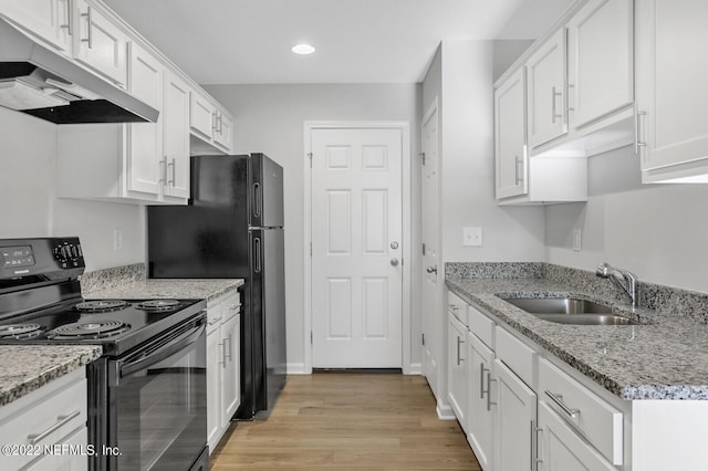 kitchen with black appliances, light stone counters, sink, light hardwood / wood-style floors, and white cabinets