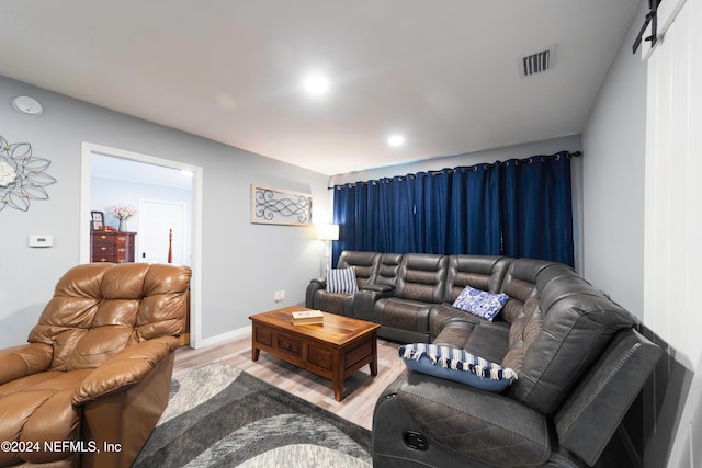 living room with a barn door and wood-type flooring