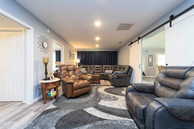 living room with a barn door and light hardwood / wood-style floors