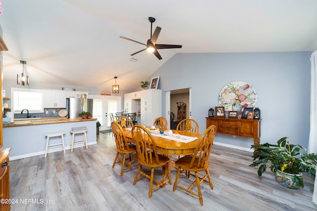 dining room with high vaulted ceiling, sink, light hardwood / wood-style floors, and ceiling fan with notable chandelier