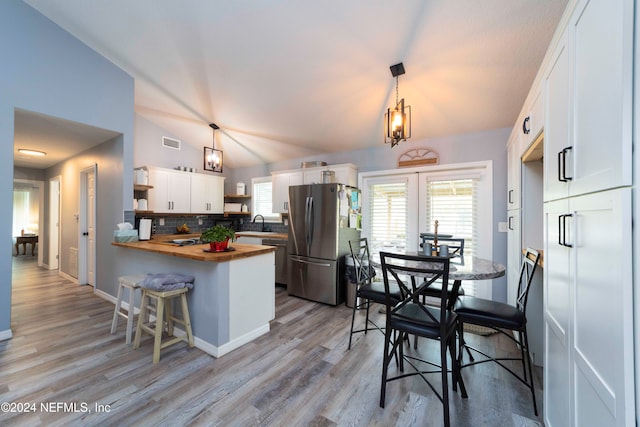 kitchen featuring white cabinets, stainless steel appliances, butcher block countertops, and hanging light fixtures