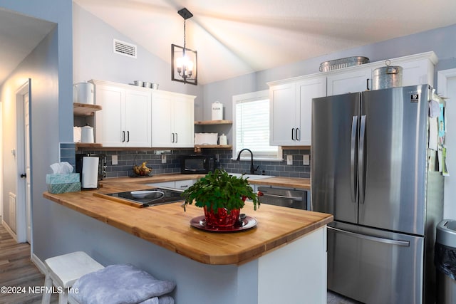 kitchen featuring butcher block counters, white cabinets, black appliances, and lofted ceiling