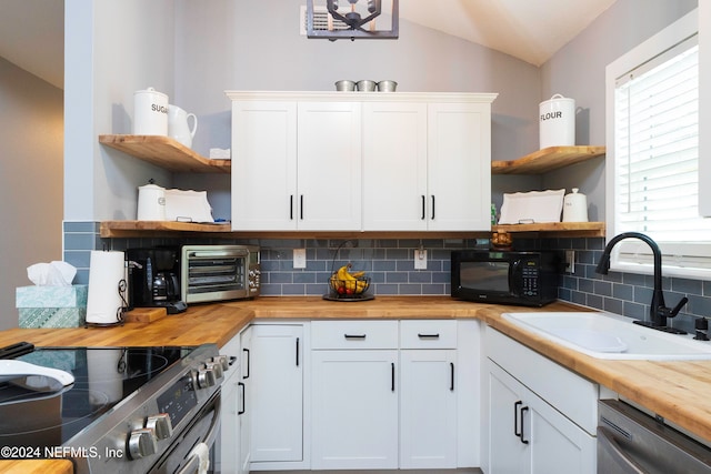 kitchen featuring butcher block counters, sink, tasteful backsplash, white cabinetry, and appliances with stainless steel finishes