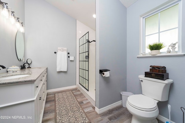 bathroom with hardwood / wood-style flooring, vanity, toilet, and walk in shower