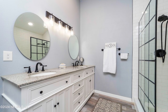 bathroom featuring vanity, wood-type flooring, and a tile shower