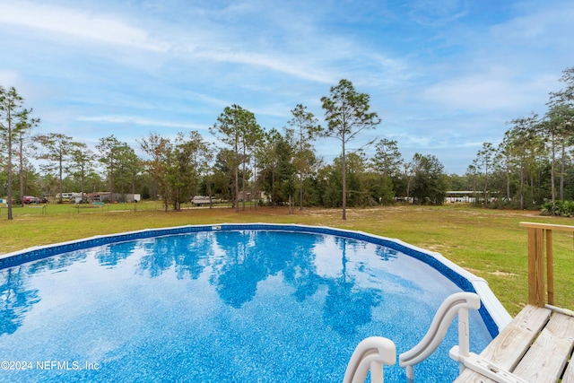 view of swimming pool featuring a yard