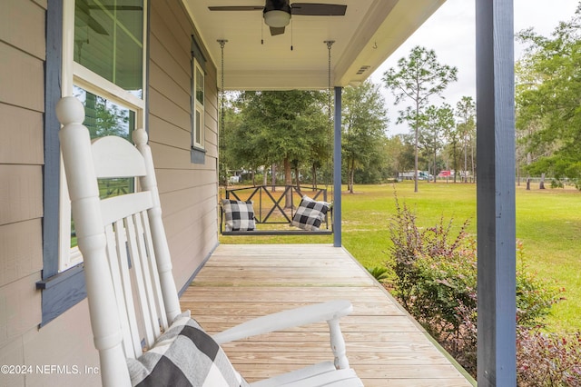 wooden terrace with a lawn, ceiling fan, and a porch