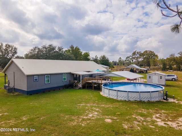 view of swimming pool with central air condition unit, a yard, a storage unit, and a deck