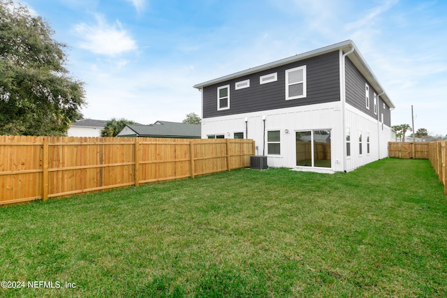 back of property featuring cooling unit and a lawn