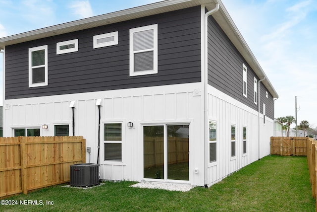 back of property with central air condition unit and a lawn