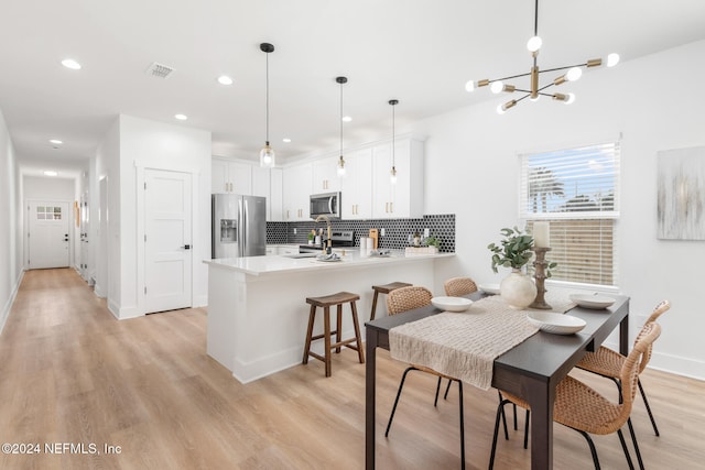 dining space with a notable chandelier and light hardwood / wood-style floors