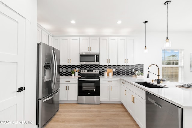 kitchen featuring hanging light fixtures, white cabinets, sink, and appliances with stainless steel finishes