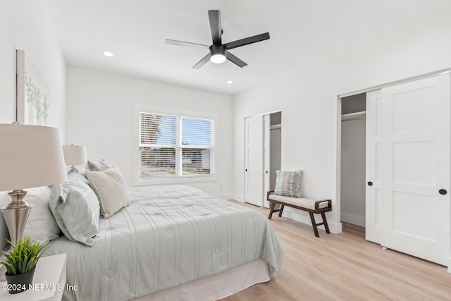 bedroom featuring multiple closets, light hardwood / wood-style flooring, and ceiling fan