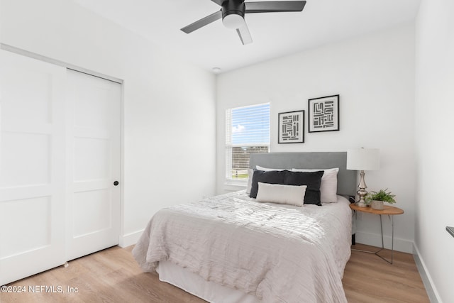 bedroom with light hardwood / wood-style floors, ceiling fan, and a closet